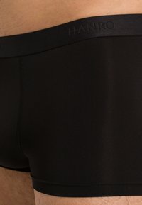 Svarta boxerkalsonger i ett slätt, elastiskt tyg med en mjuk midja som bär logotypen "HANRO." Har en åtsittande passform och minimal sömnad.
