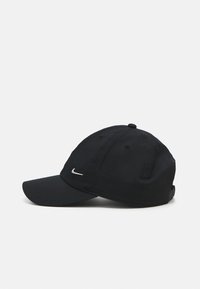 Casquette de baseball noire avec une visière incurvée, fabriquée en tissu lisse, arborant un petit logo Nike en argent à l'avant et des œillets de ventilation.