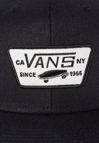 Cappellino nero con una toppa ricamata rettangolare bianca che presenta "VANS", una grafica di skateboard e il testo "CA" e "NY" con "SINCE 1966."