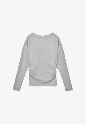 Camicia a maniche lunghe grigio chiaro con scollo rotondo e leggere arricciature ai lati, distesa su uno sfondo bianco.