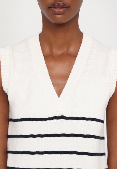 Weißer Strickpullover mit V-Ausschnitt und kurzen Ärmeln, mit dunkelblauen horizontalen Streifen und gerippten Abschlüssen. Glatte Textur, lässiges Design.