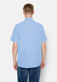 Camisa de cuadros azul de manga corta con cuello abotonado, fabricada en un tejido ligero y con un dobladillo curvado, combinada con jeans azules.