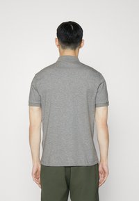 Polo gris avec un col et des manches courtes, au tissu lisse et épuré. La vue arrière montre une coupe droite et des coutures discrètes.