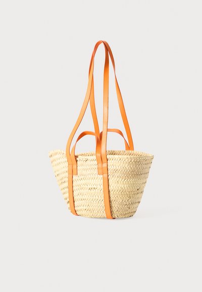 Vævet stråindkøbstaske med kraftige orange læderstropper, prydet med en rund form og åben design. Letvægts og tekstureret overflade.