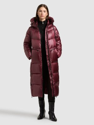 Maroon puffer coat with a hood, featuring a quilted design, zippered pockets, and a sleek, glossy finish. Worn over a black sweater and black boots.