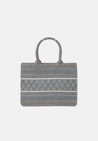 Tote taske i blåt stof med indviklet lyst mønster. Designet har to runde håndtag og en rektangulær form med dekorative accenter.