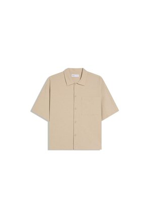 Béžová košeľa s krátkym rukávom na gombíky, s golierom a jedným náprsným vreckom, zobrazená položene na bielom pozadí.