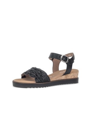 Black leather sandal with woven front strap, adjustable ankle buckle, cork wedge heel, and ridged black sole on white background.