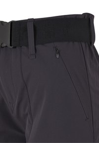 Közelkép sötétszürke nadrágról, fekete állítható övvel és cipzáros oldalzsebbel a jobb csípőnél.