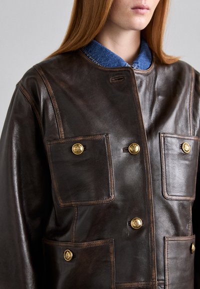 Bruine leren jas met een hoge kraag, voorzien van vier voorzakken en goudkleurige knopen. Geconfigureerd oppervlak en contrasterende blauwdenim binnenzijde.