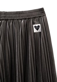 Falda plisada metálica en gris con una cinturilla elástica. Presenta una etiqueta con un logo de corazón y el nombre de la marca "IKKS". Textura suave.