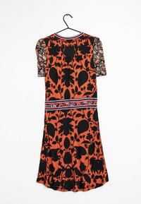 Buntes Kleid mit orangefarbigem Grund und schwarzen Blumenmustern. Kurze Ärmel mit einem gemusterten Schulterdesign und einem dekorativen Taillenband.