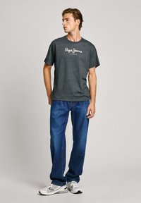 Grå bomulls T-skjorte med "Pepe Jeans London" logo, kombinert med blå denimjeans. Ledig passform, korte ermer, minimalistisk design.
