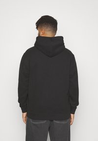 Black hooded sweatshirt with a relaxed fit, made of soft fabric. Features a large hood and ribbed cuffs and hem. No visible branding.
