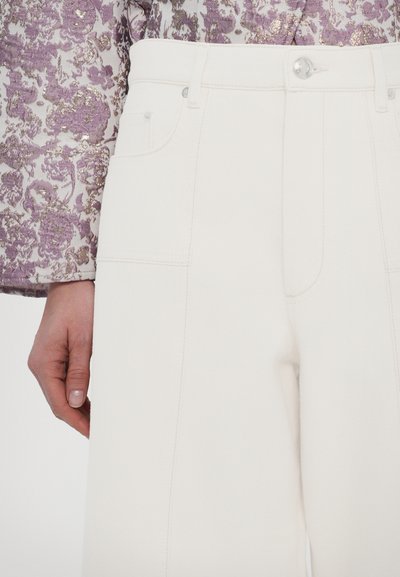 Witte denim broeken met een hoge taille en wijde pijpen, voorzien van voorzakken en subtiele stiksels. Gecombineerd met een top met een bloemmotief.