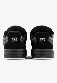 Black sneakers featuring a mix of smooth and textured materials, a cushioned collar, and a white sole. Upper displays a subtle logo accent.