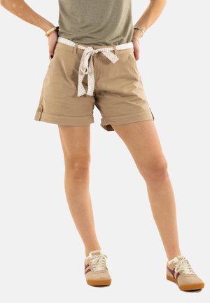 Pantalones cortos caqui con un cinturón blanco trenzado, que presentan botones en la parte delantera y dobladillos enrollados. Combinados con zapatillas beige con rayas rojas.