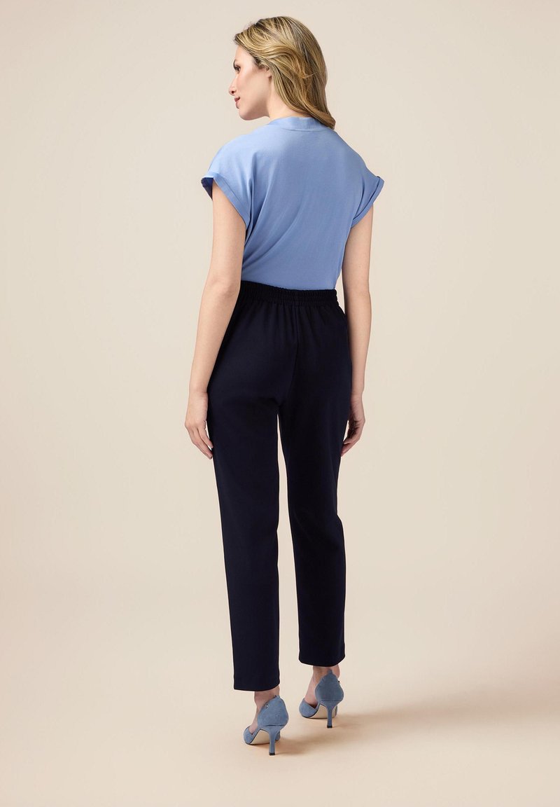 Top de manga corta azul claro combinado con pantalones de cintura elástica azul marino; modelo lleva zapatos de tacón alto azul claro; textura de tela suave.