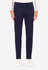Pantaloni chino blu navy a taglio slim, realizzati in tessuto misto cotone. Presentano chiusura con bottoni, tasche angolate e orlo semplice. Abbinati a sneakers bianche.