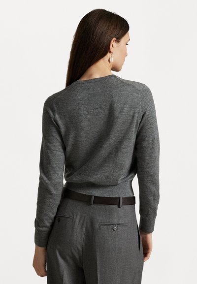 Grå strikkegenser med lange ermer og rund hals. Brukt med grå skreddersydde bukser med belte og baklommer. Enkelt design.