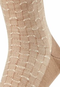 Beige Sock mit strukturiertem Muster, das ein Rautendesign in Weiß aufweist. Glattes Strickgewebe mit verstärktem Zehenbereich.