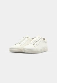 Baskets blanches en cuir avec une finition texturée, bout rond et lacets plats. Design minimaliste avec une semelle en caoutchouc.