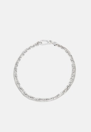 Bracelet à double chaîne argentée avec maillons entrelacés et fermeture à fermoir sur fond blanc uni.