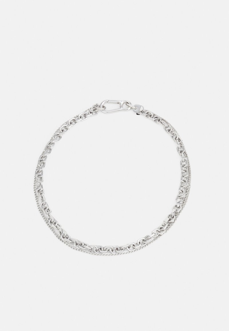 Bracelet à double chaîne argentée avec maillons entrelacés et fermeture à fermoir sur fond blanc uni.