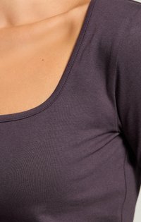 Violetti pitkähihainen paita, jossa on leveä avonainen kaula-aukko, valmistettu pehmeästä ja joustavasta kankaasta. Sujuva pinta, jossa on minimoidut saumat reunoilla.