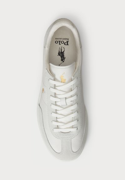 Sneaker bianca in pelle con pannelli testurizzati, design con lacci e dettaglio del logo dorato. Presenta un interno imbottito e una suola liscia.