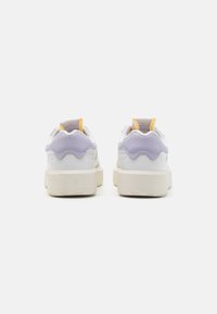 Zapatillas blancas con acentos en lavanda y amarillo, cuero texturizado, diseño de talón ondulado y suela de goma gruesa y resistente.