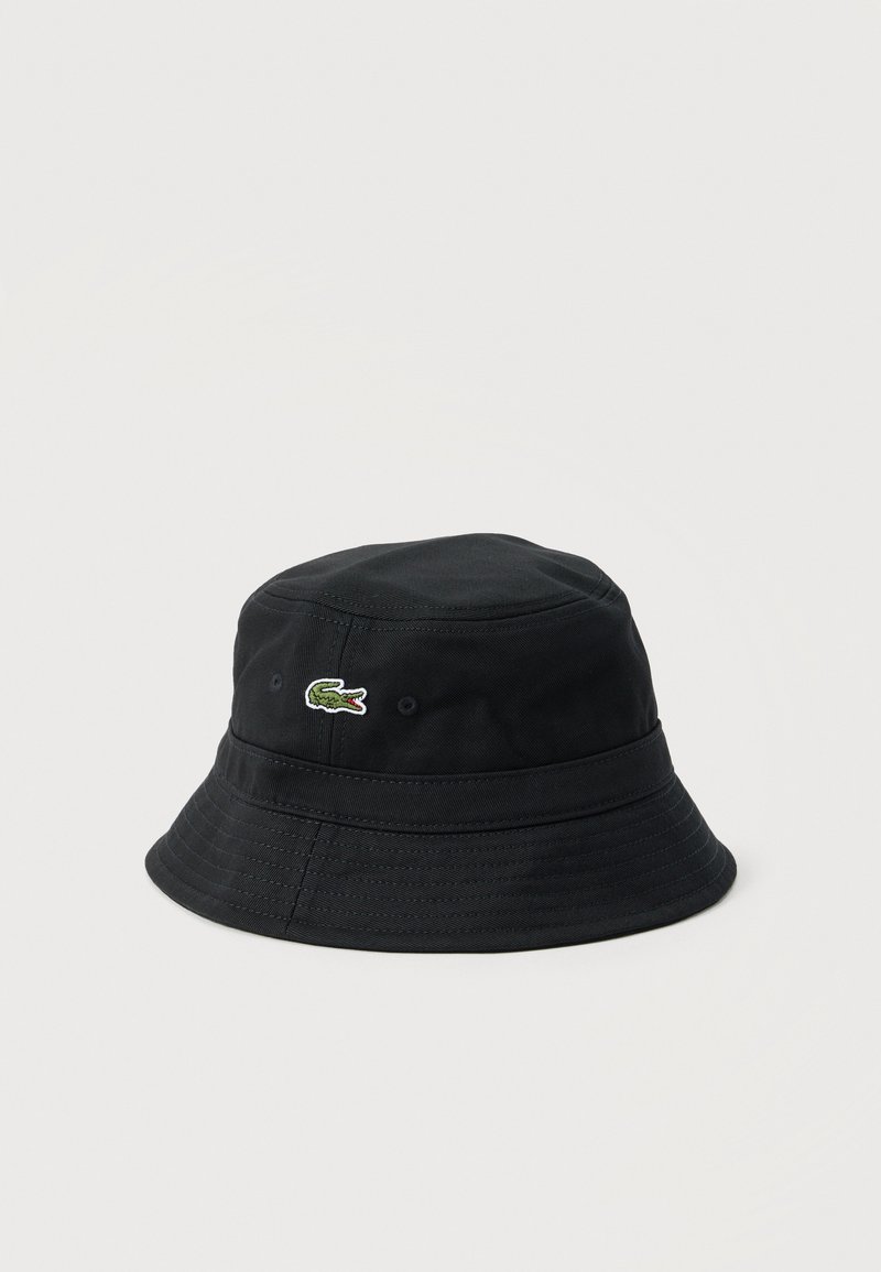 Μαύρο καπέλο τύπου bucket με φαρδύ γείσο και μικρό πράσινο λογότυπο κροκοδείλου στο μπροστινό μέρος, μονόχρωμο φόντο.