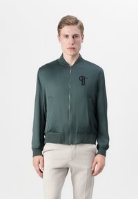 Green bomber jacket in smooth, matte fabric, featuring a front zipper, ribbed cuffs, and two side pockets. Black logo on the chest.