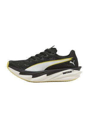 Zwarte en gele Puma Nitro Elite hardloopschoen met dikke witte en zwarte zool, wit Puma-logo en veterontwerp.