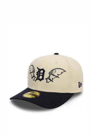 Beige and black baseball cap with stylized D logo flanked by bat wings embroidery on front and size sticker on black brim.