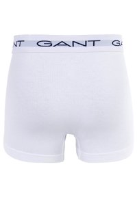Weiße Baumwoll-Boxershorts mit einem weichen, elastischen Bund, der das "GANT"-Logo in Marineblau trägt. Glatte Textur, mittellanges Design.