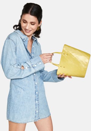 Robe chemise en denim bleu clair avec des manches longues, fermeture à boutons et poches latérales, assortie à un sac à main jaune brillant avec des poignées courtes.