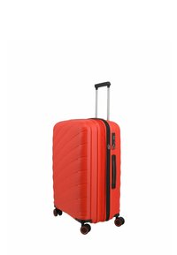 Valigia rigida rossa con un design testurizzato e ondulato, quattro ruote, manico allungabile e zip e dettagli neri.
