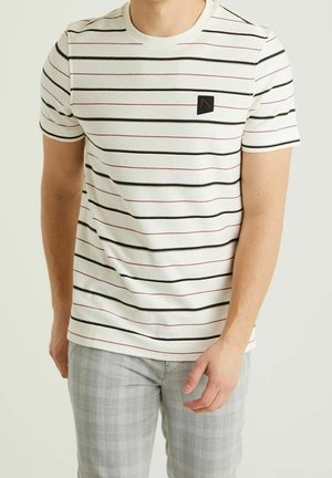 T-shirt à manches courtes blanc avec des rayures horizontales noires et roses, avec un petit écusson logo noir sur la poitrine. Matière en coton doux.