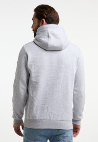 Grau Hoodie aus weichem Stoff, mit einer großen Kapuze und gerippter Saumkante, nahtlosem Rücken und minimalistischem Branding am Hals.