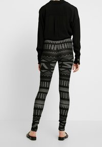Černé legíny s geometrickým, monochromatickým potiskem. Zakoupeno s dlouhým černým topem a černými plochými sandály. Texturovaný, přiléhavý design.