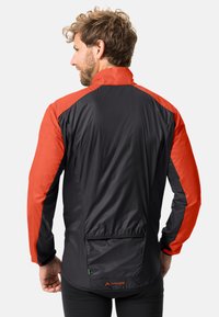 Giacca a vento nera e arancione con colletto alto, tasca con zip sul retro e texture leggera e morbida.