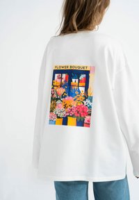 Witte langemouwen shirt met een kleurrijke "Bloemenboeket" grafiek met bloemdesigns in levendige tinten op de achterkant. Casual pasvorm.