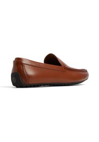 Mocasines de cuero marrón con un acabado suave, diseño sin cordones, puntera redondeada, costuras decorativas y una suela exterior de goma negra texturizada.