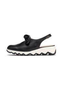 Zapato slingback de piel negra con un acento anudado, que presenta una suela de plataforma blanca con zigzag y una textura suave y brillante.