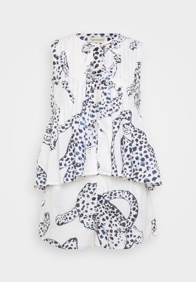 Top sans manches blanc avec imprimé léopard noir et bleu, présentant un ourlet volanté et une fermeture à bouton. Associé à un short assorti.