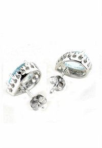 Pendientes de plata con un diseño curvado, que presentan una gema azul y acentos decorativos en forma de llama a lo largo del borde. Con cierre de presión seguro.
