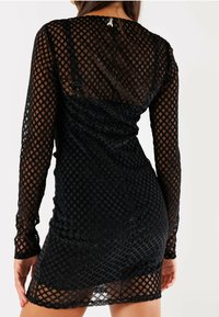 Miniabito nero con maniche lunghe e design a reticolo testurizzato. Realizzato in materiale trasparente con una leggera lucentezza. Chiuso sul retro.