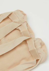 Bolsa de tela nude con textura suave, cuenta con dos asas beige. El diseño incluye costuras cosidas y una superficie lisa y sin adornos.