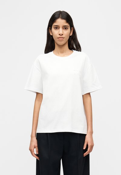 Λευκό βαμβακερό T-shirt με στρογγυλή λαιμόκοψη και κοντά μανίκια, με μικρό λογότυπο στην πάνω αριστερή πλευρά του στήθους.
